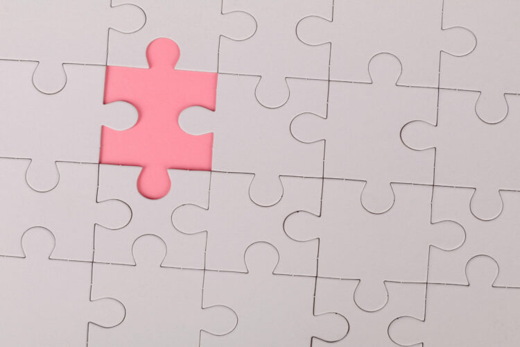 A white jigsaw with one piece missing, showing as a pink gap